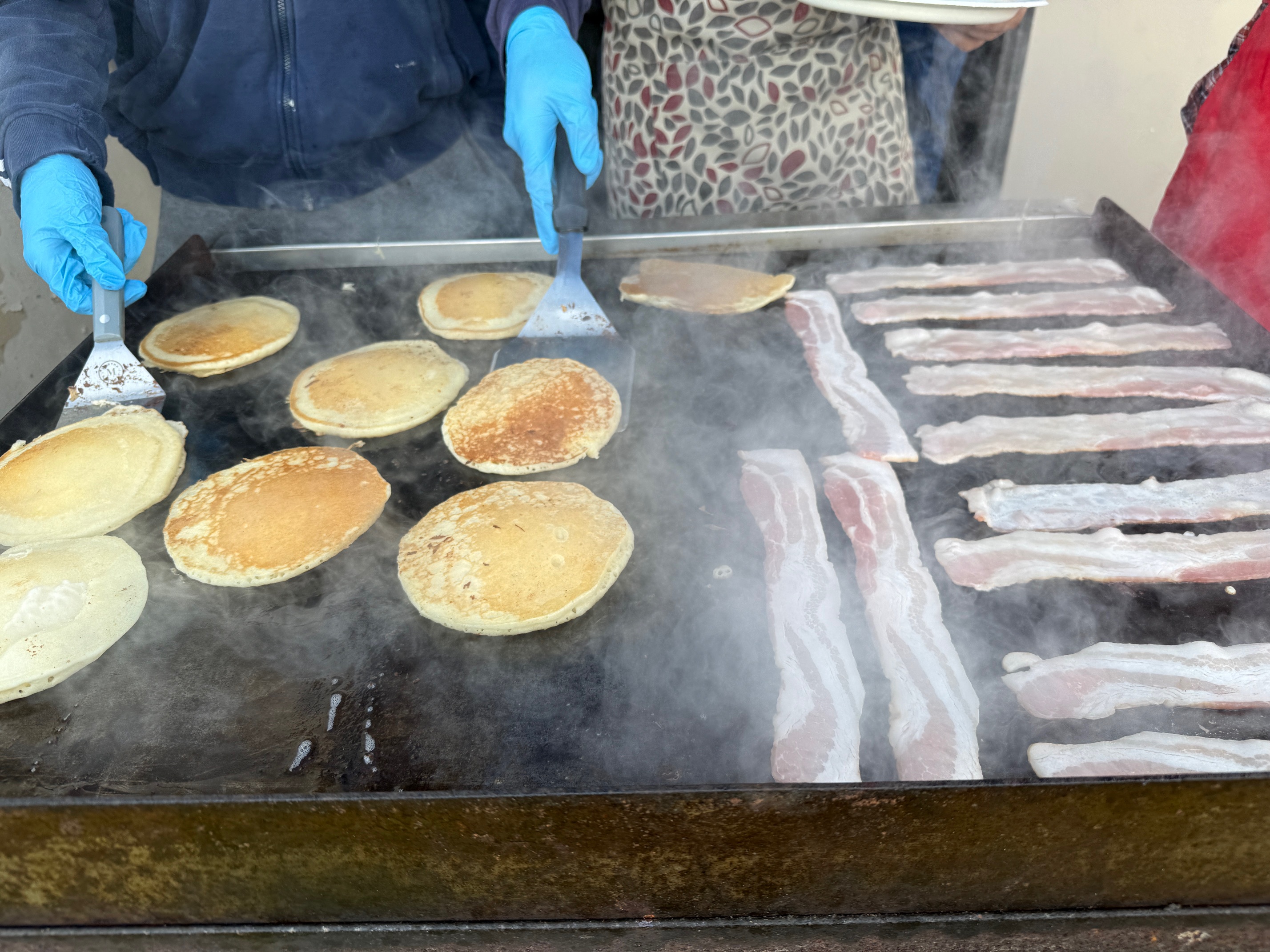Pancakes and bacon cooking on the griddle